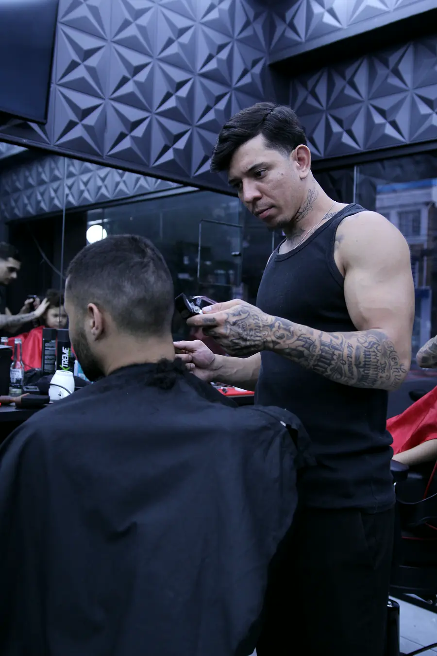 Barbeiro trabalhando o topo do cabelo diante do espelho
